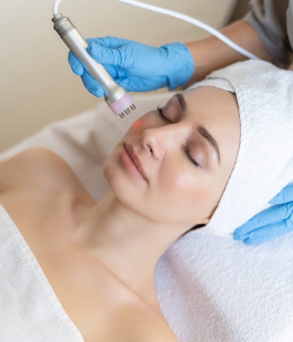 Young woman lying on cosmetologist’s table during rejuvenation procedure. Cosmetologist take care about neck and face skin youthfull and wellness. Hardware face cleaning procedure Young woman lying on cosmetologist's table during rejuvenation procedure. Cosmetologist take care about neck and face skin youthfull and wellness. Hardware face cleaning procedure
